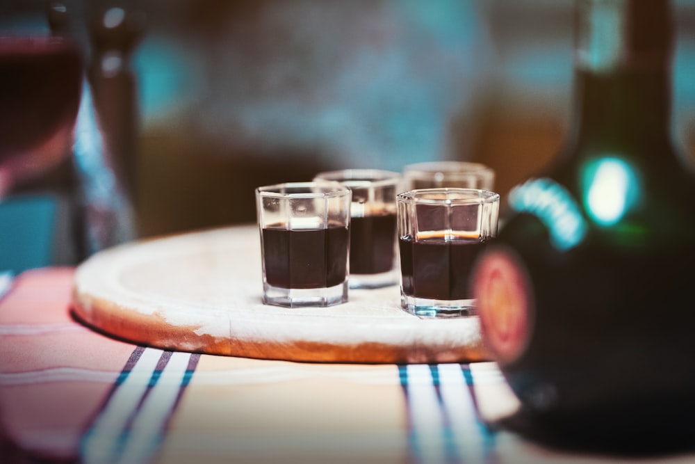 four clear drinking glasses on top of brown board