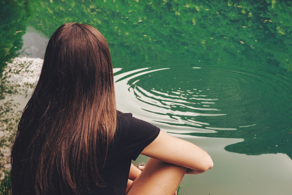 woman sitting beside body of water