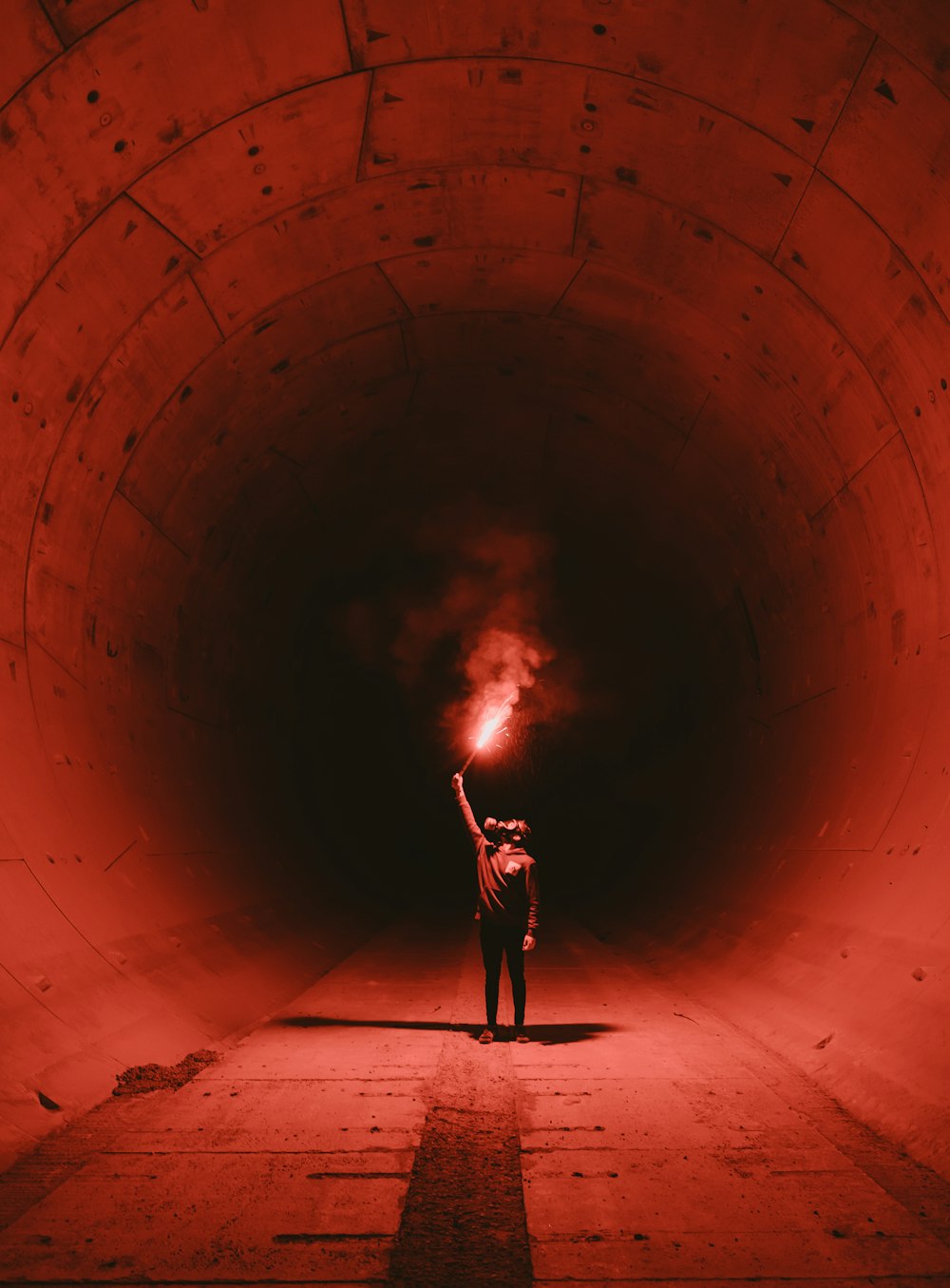 man wearing gas mask holding torch inside tunnel