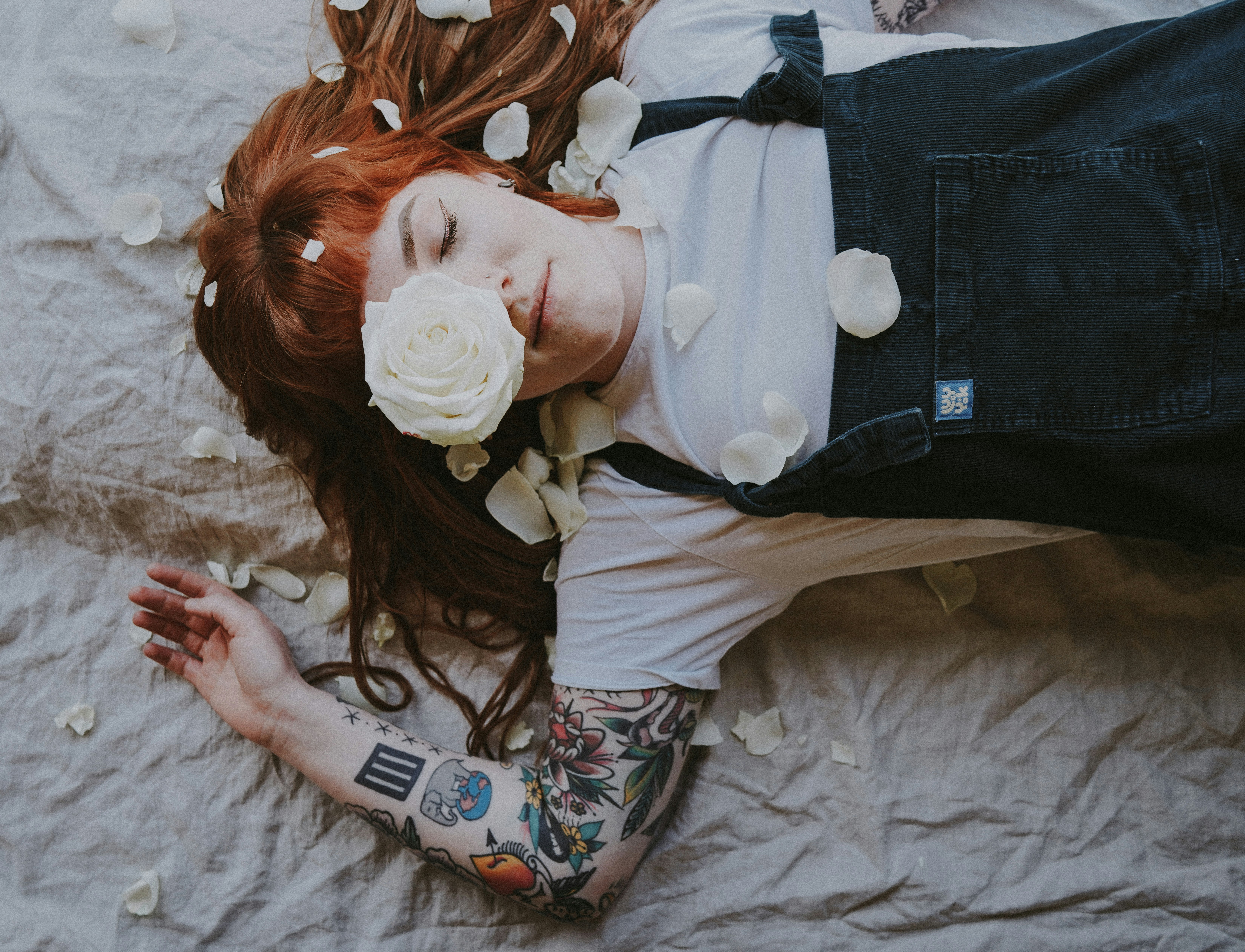 woman with tattoo laying on gray textile with white roses