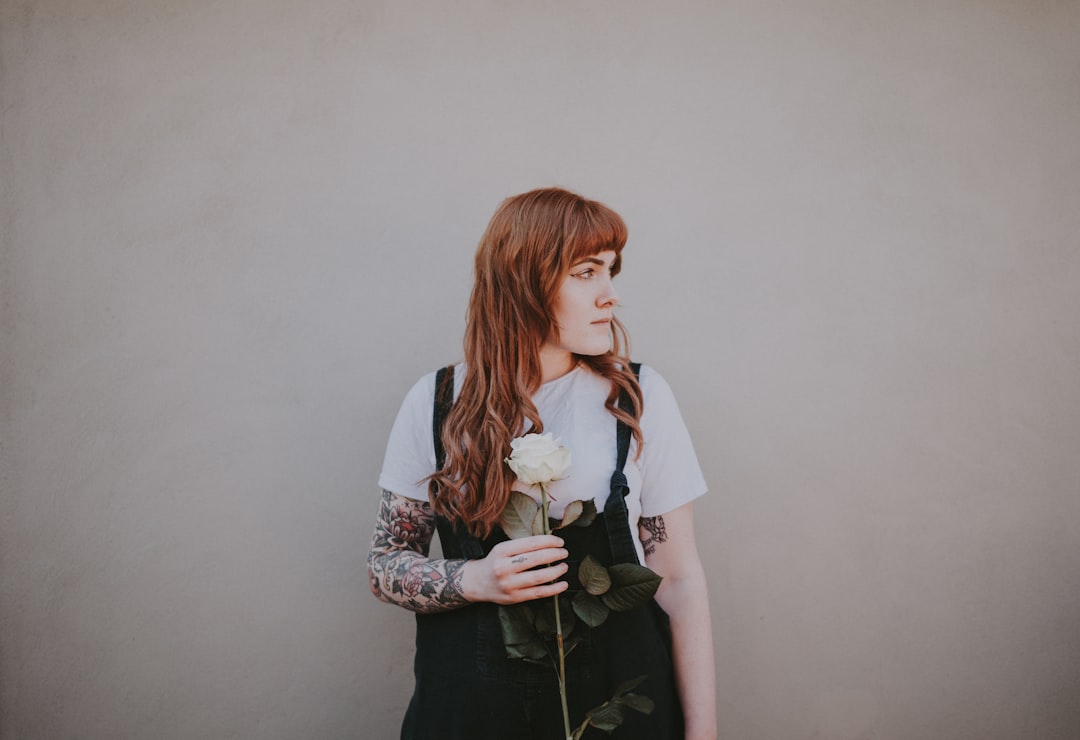 woman holding white rose looking at her left side