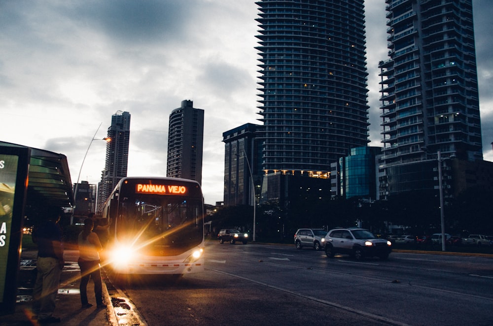 Panama Veki bus on highway beside high-rise building during night time