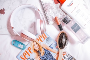 A flat lay of self-care essentials including scented candles, skincare products, and a soft knit blanket