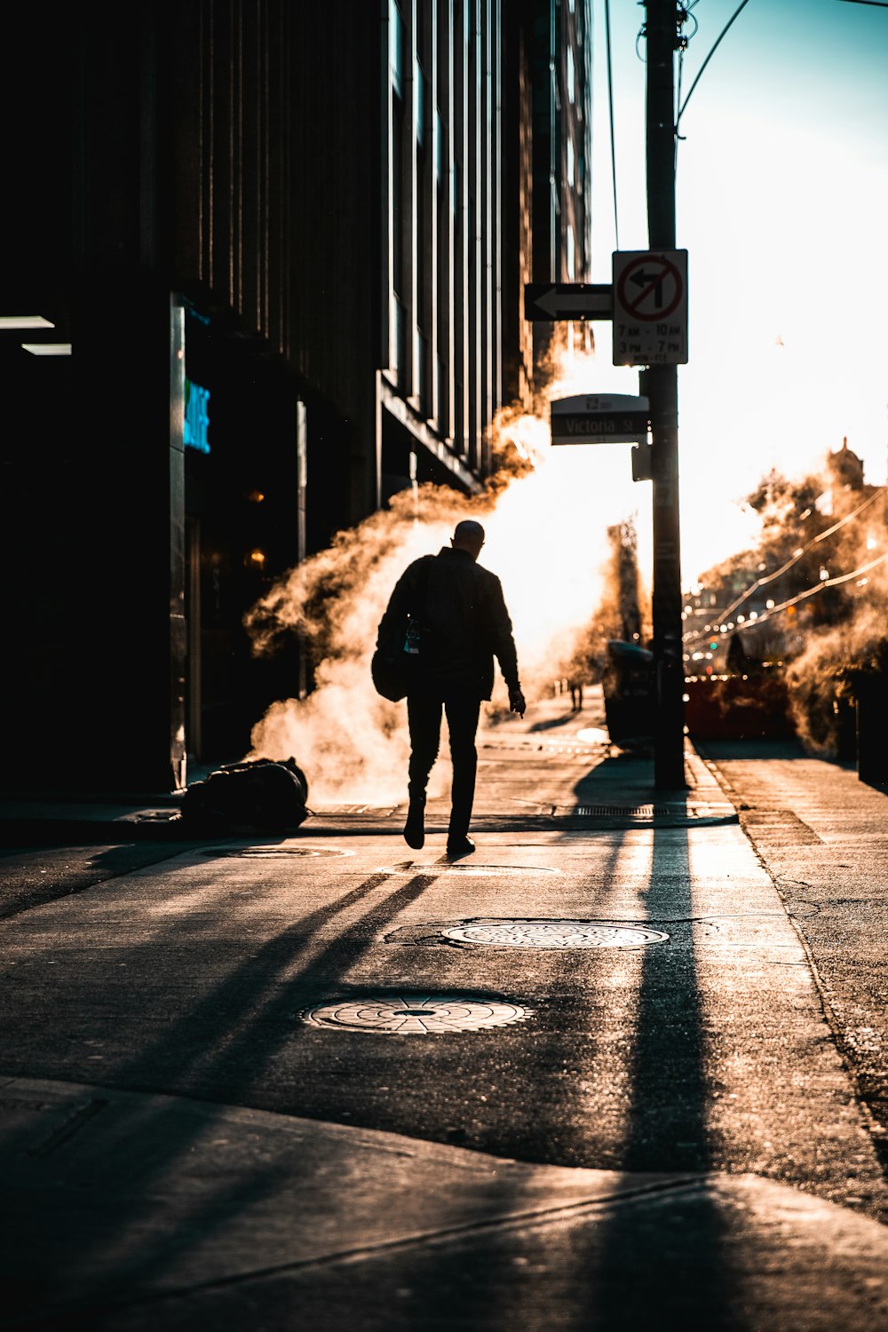 man in black jacket walking on the road