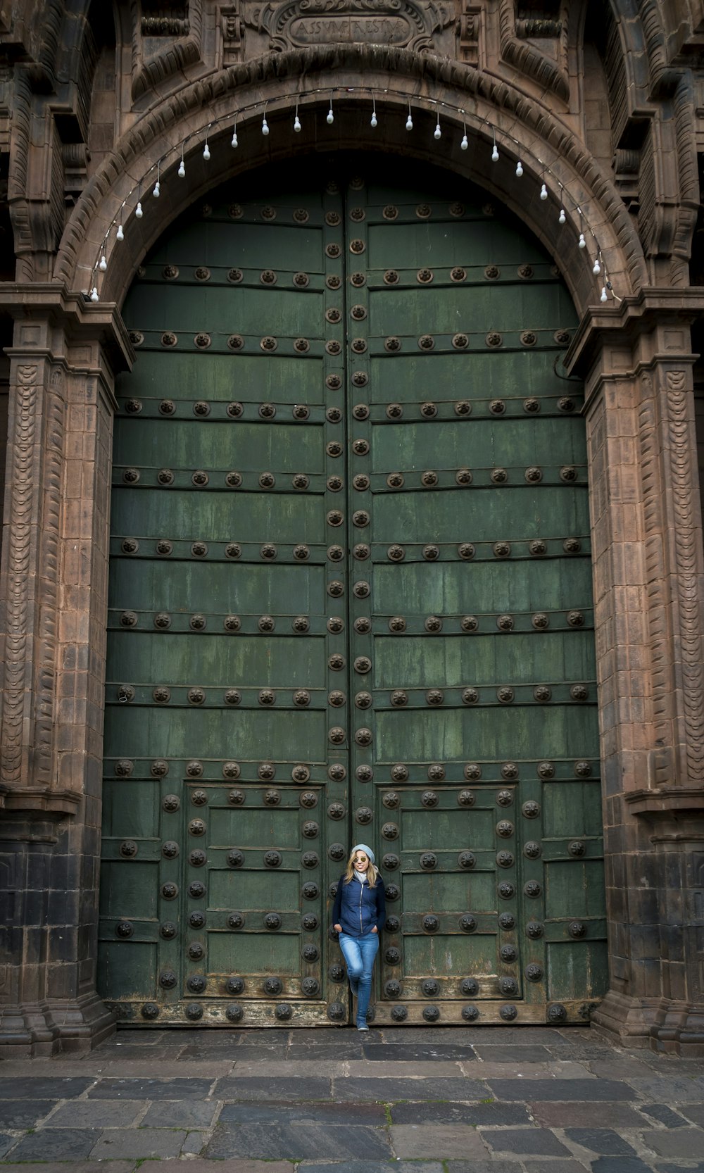 Mujer apoyada en una gran puerta verde