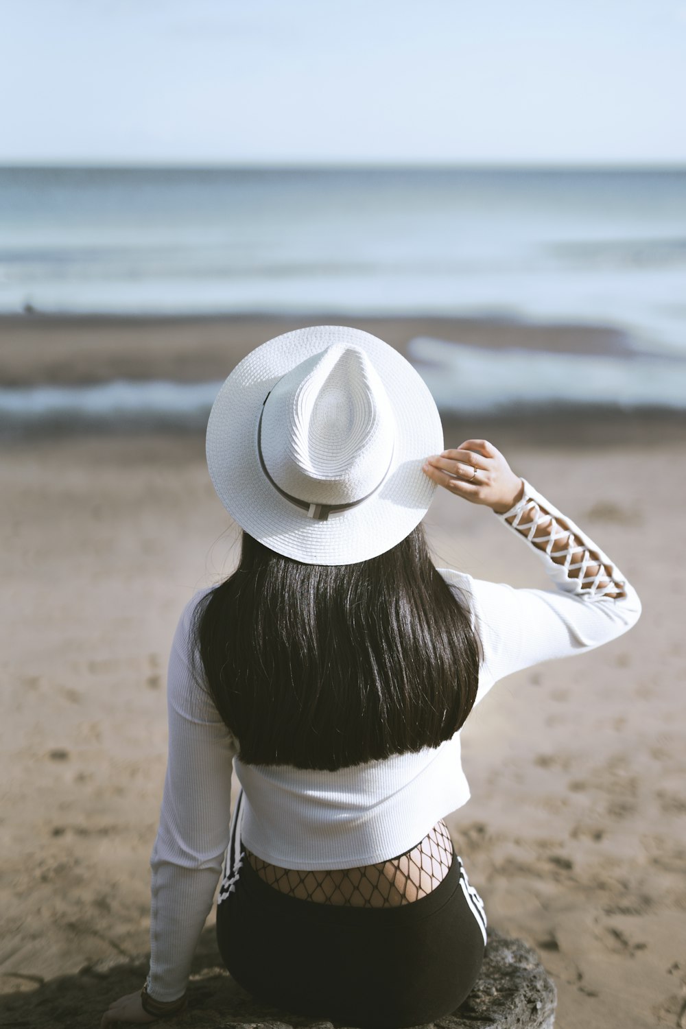 woman sits on rock watching ocean