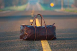 Close-up of a durable travel duffle bag on a gravel path with mountains in the background.