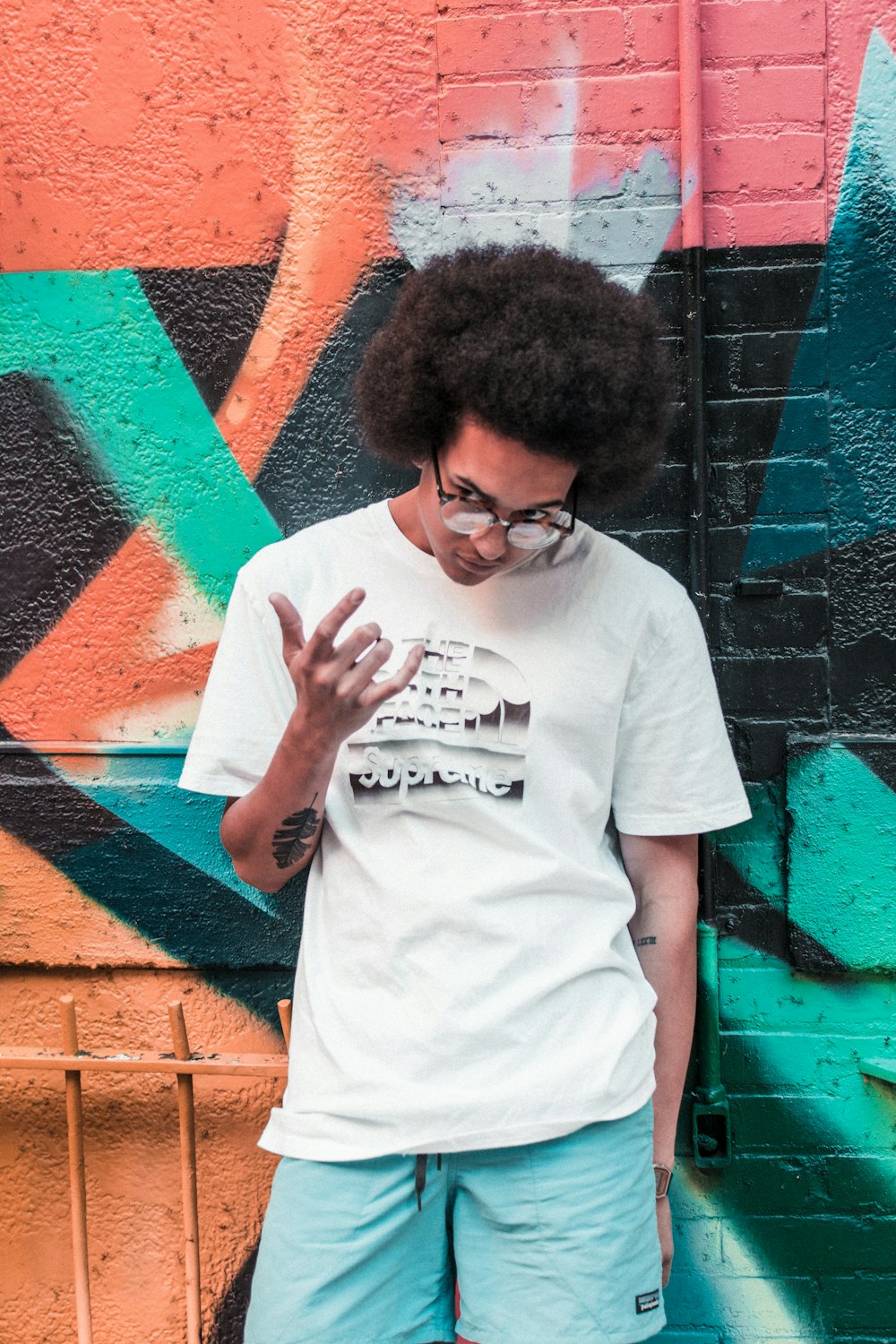 man wearing black framed eyeglasses standing near printed wall