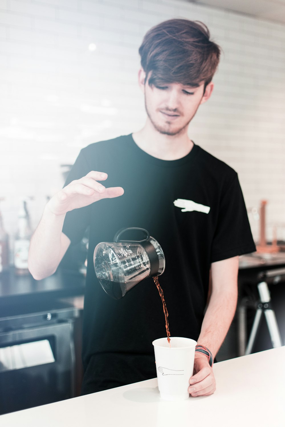 uomo che versa liquido su tazza bianca