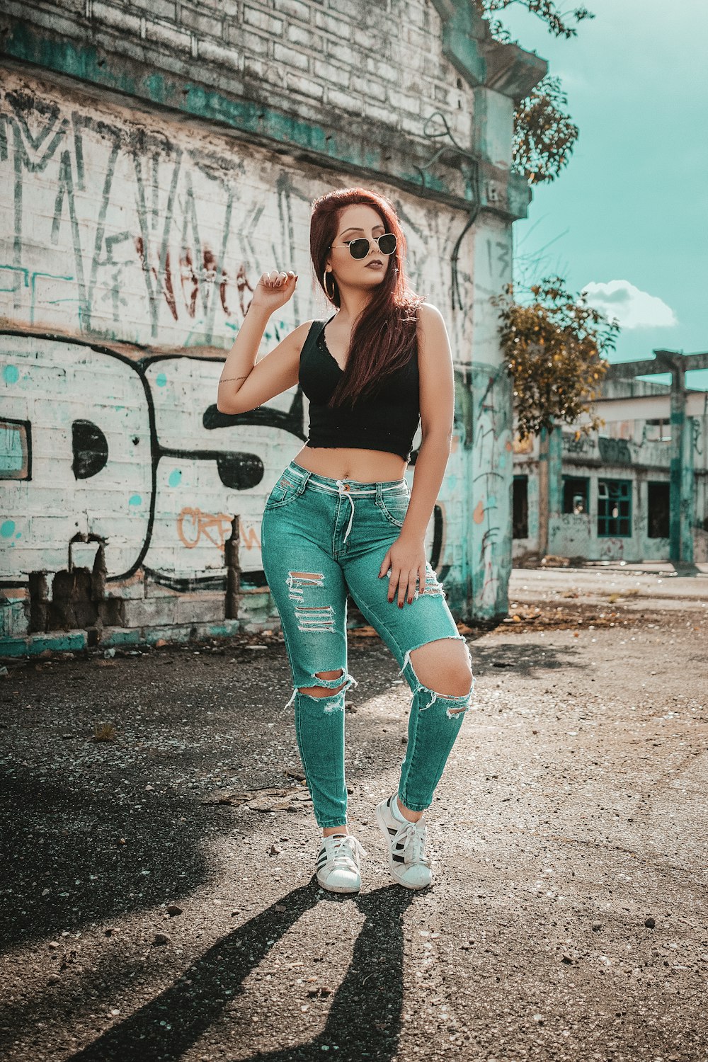 femme portant un haut sans manches noir à col en V et un pantalon en jean bleu vieilli tout en prenant une photo