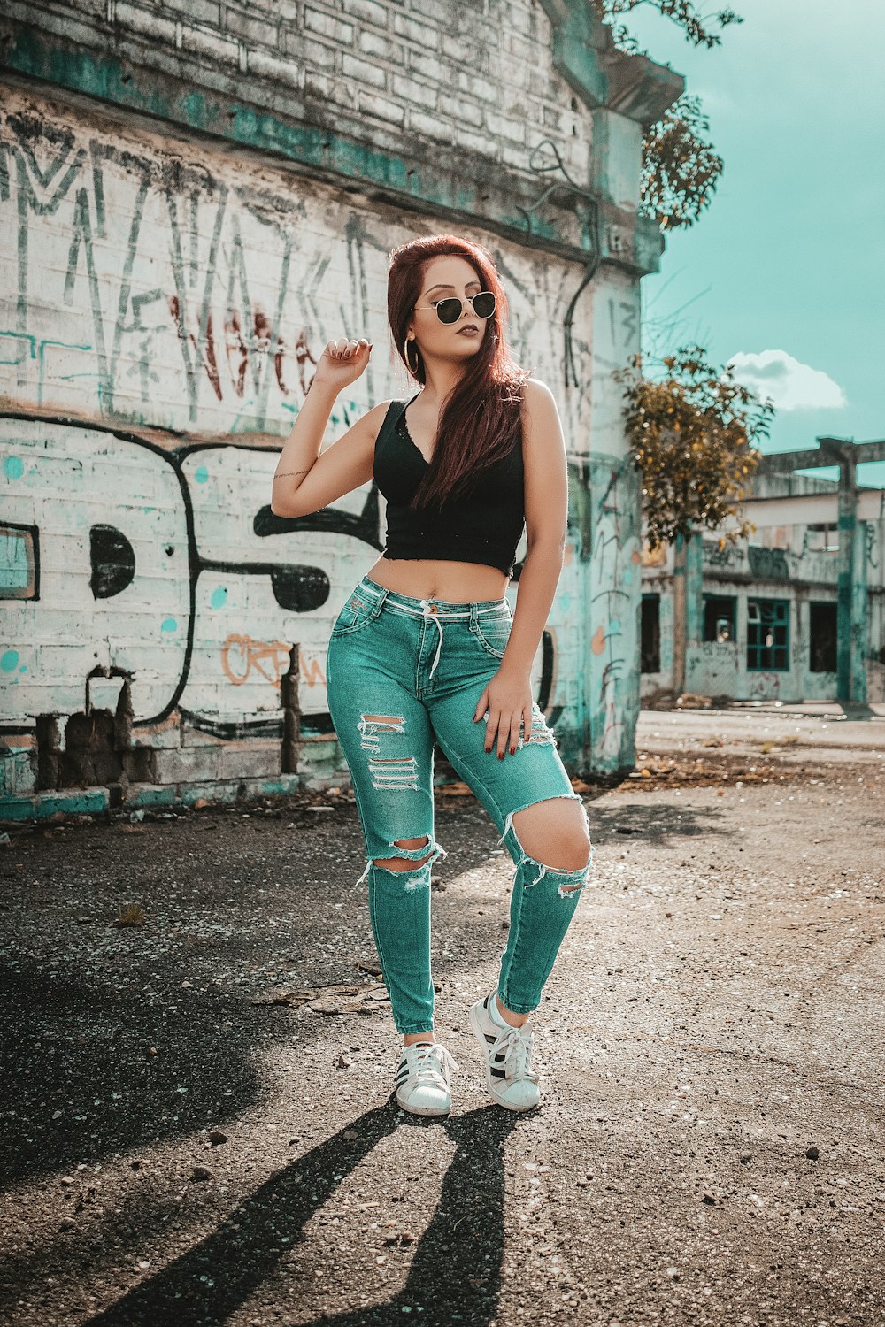 woman wearing black V-neck sleeveless top and distressed blue denim pants outfit while taking photo