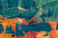 A vibrant abstract painting featuring bold brushstrokes and contrasting colors. The artwork displays a mix of teal blue and vivid orange with hints of yellow, creating a dynamic and textured composition.