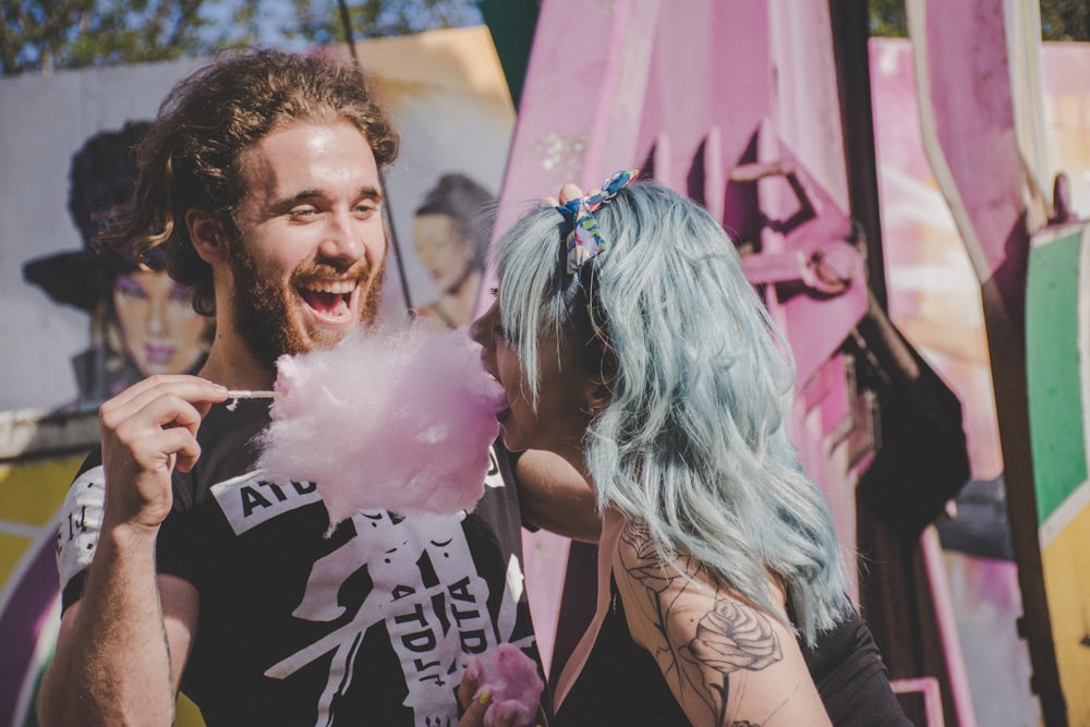 Mann und Frau lachen, während sie Zuckerwatte essen