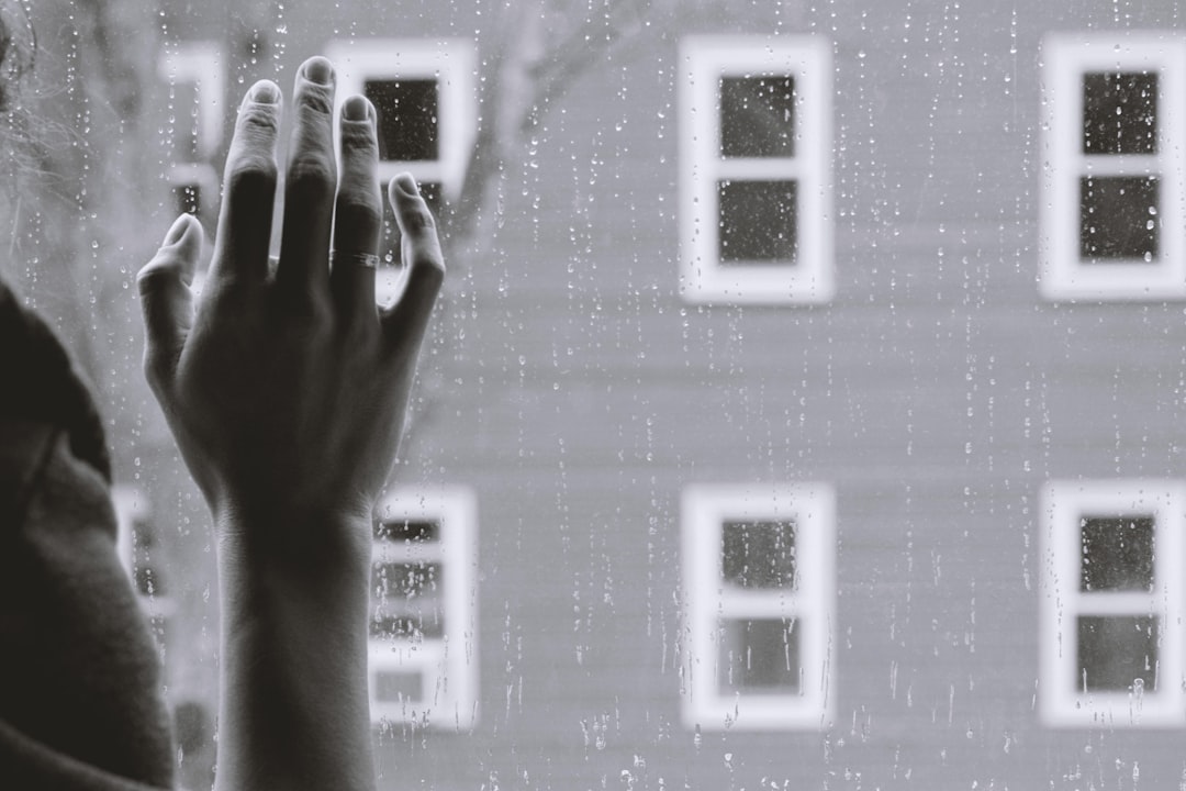  grayscale photo of woman right hand on glass window