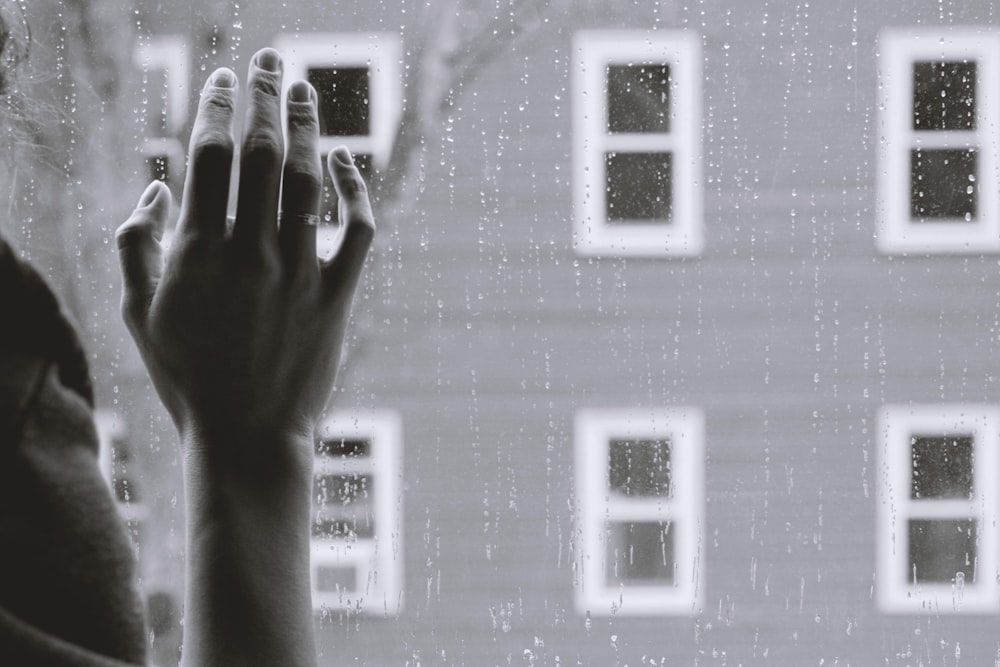 Photo en niveaux de gris de la main droite d’une femme sur verre