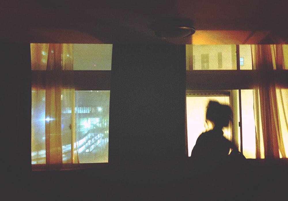 Silhouette einer Frau, die vor dem Fenster steht