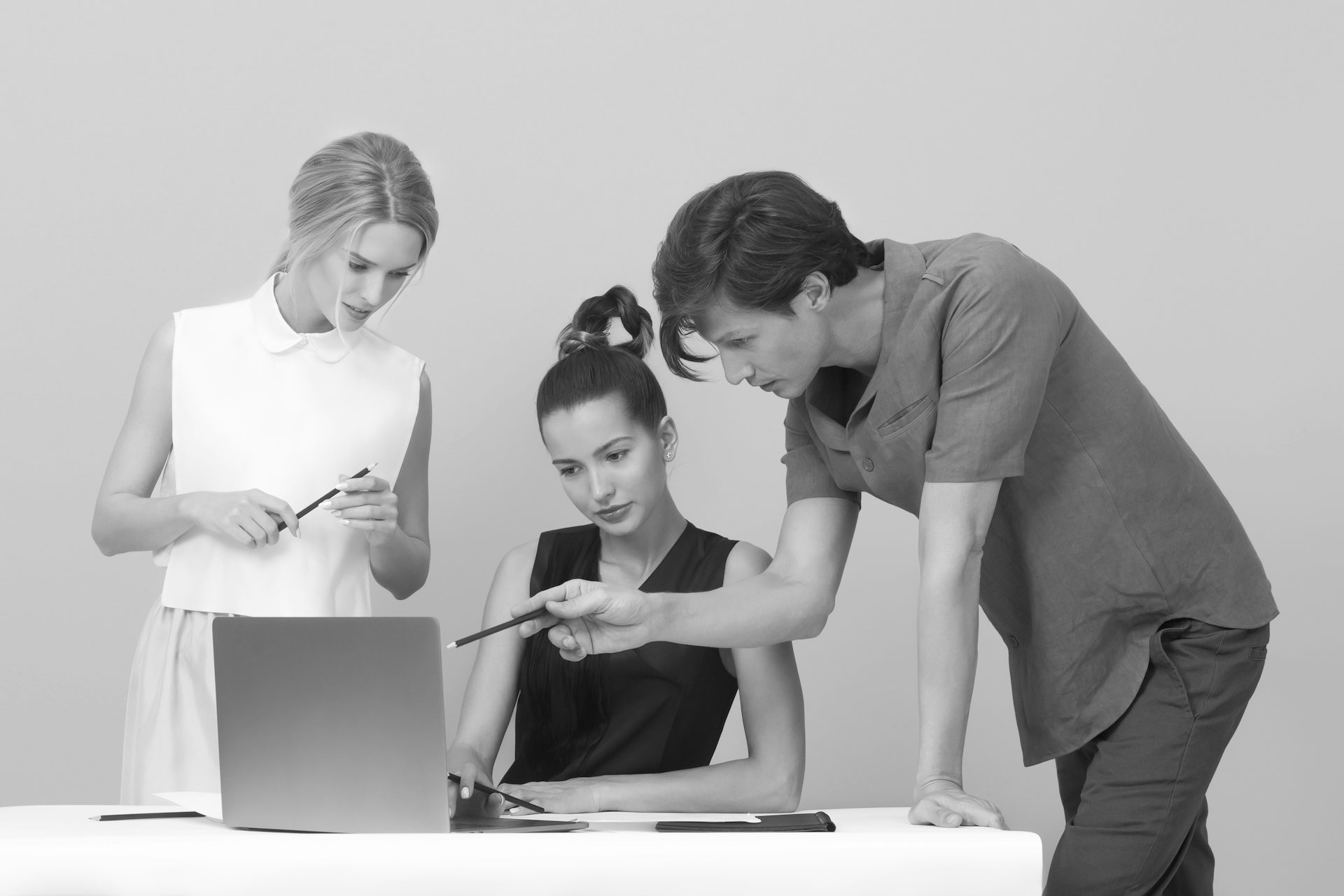 A group of people (Two male and one Female) sitting around a computer.