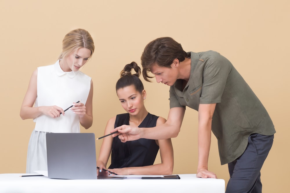 homem ensinando a mulher enquanto aponta no laptop cinza