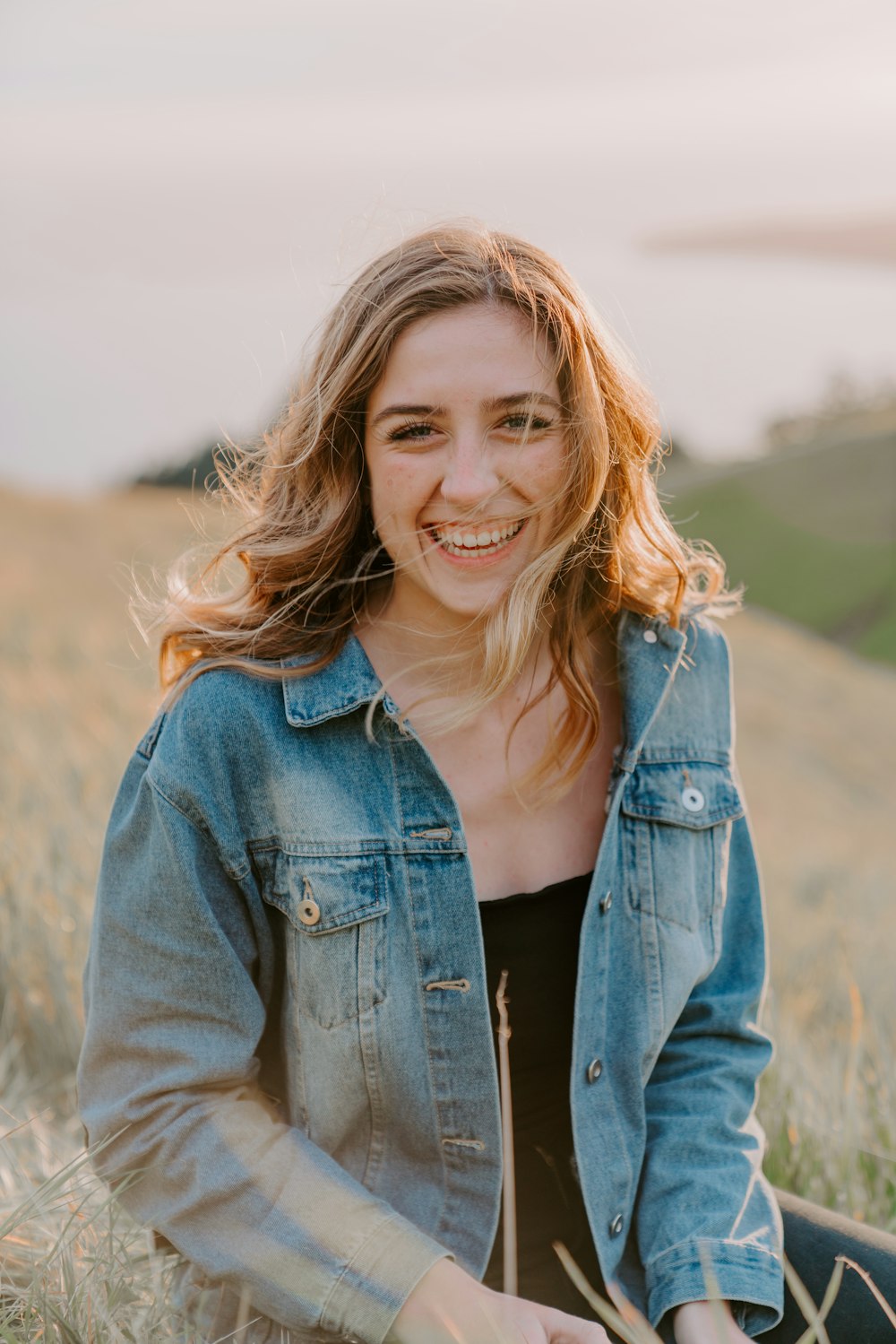 smiling woman sitting on grass during daytime