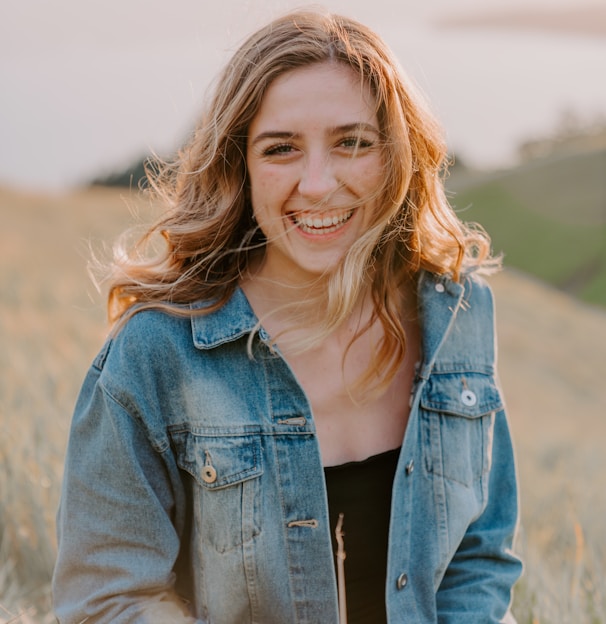 smiling woman sitting on grass during daytime