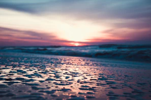 A serene sunset scene with a model in a flowing beach cover-up, the colors blending softly with the sky and sea.