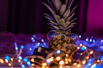 eyeglasses on pineapple surrounded with string light