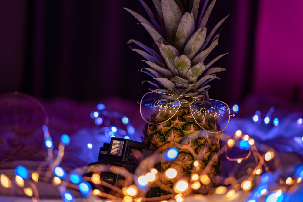 Brille auf Ananas, umgeben von Lichterkette