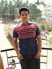 A casual outfit featuring a navy and white striped polo shirt paired with light jeans on a sunny day.