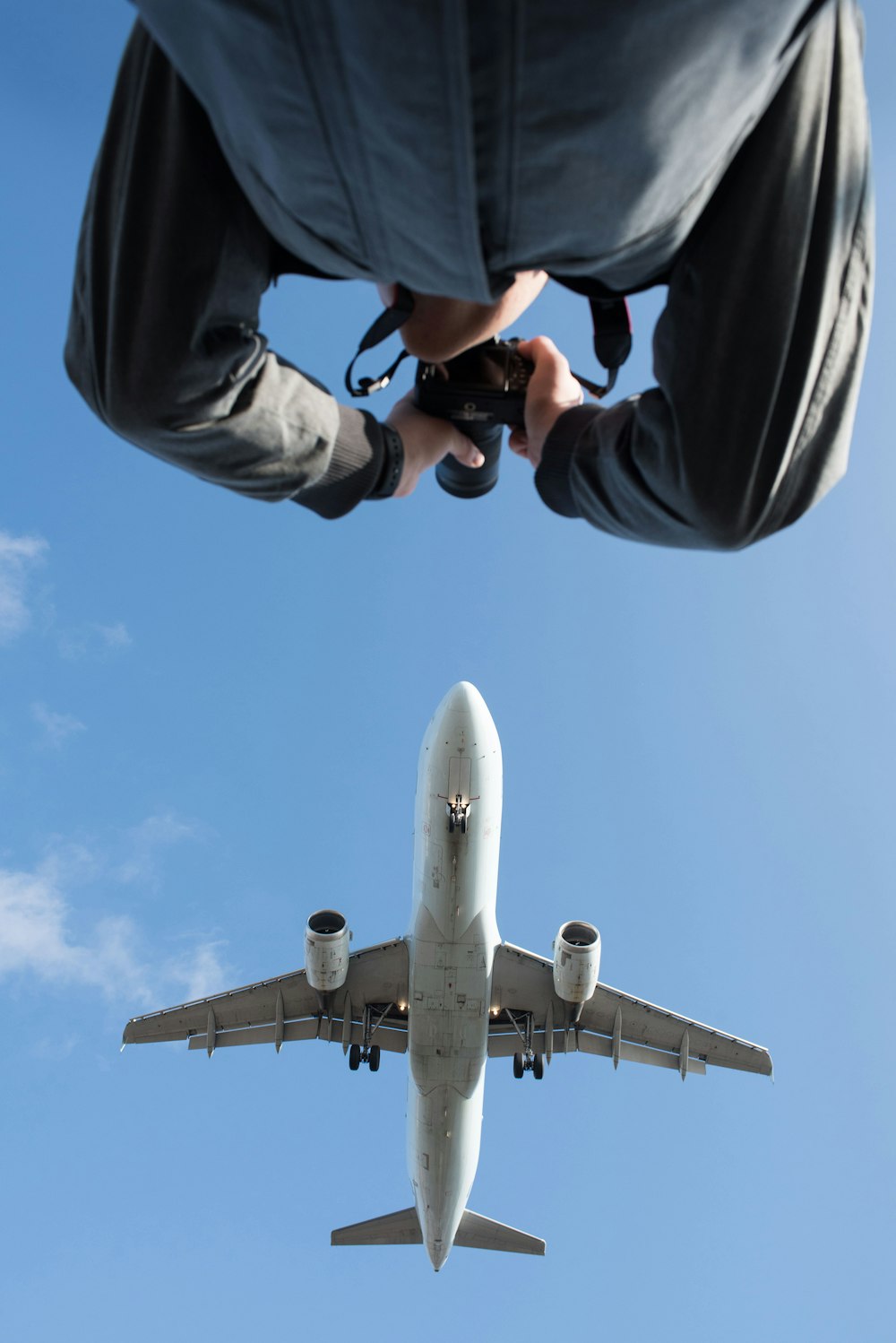 low angle photography of man taking photo of plane during daytime