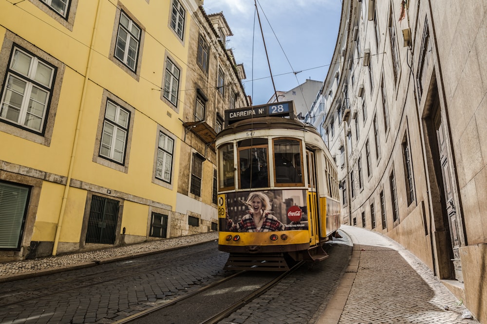 yellow tram car in between buildings