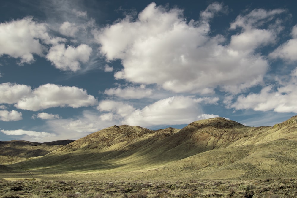 fotografia di paesaggio di montagne coperte di erbe verdi sotto il cielo nuvoloso