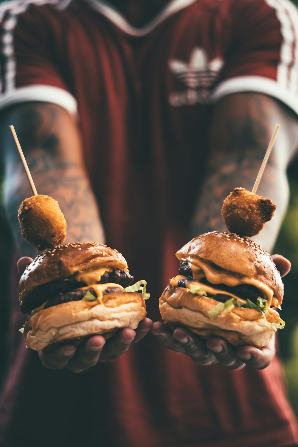 person holding two cheese hamburgers