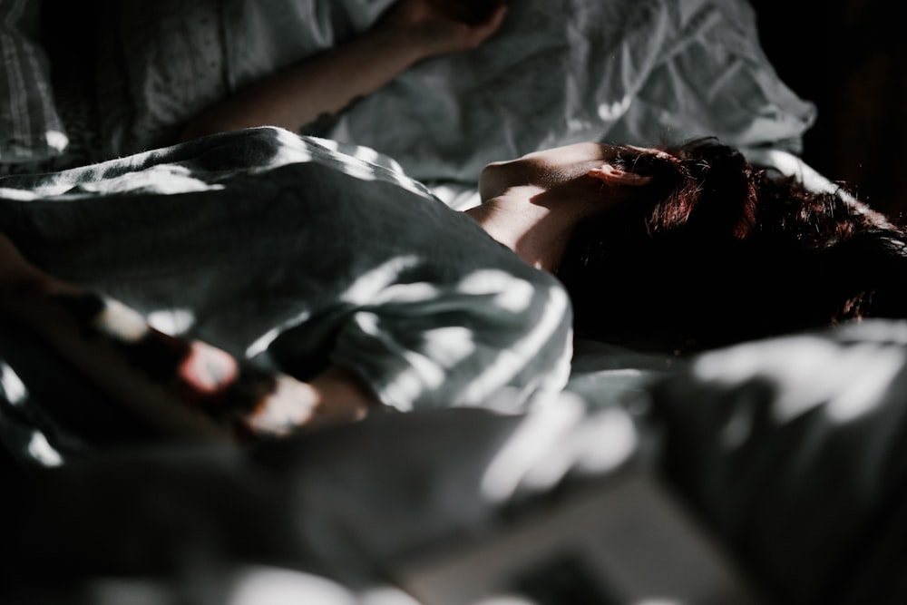 a person laying in a bed under a blanket