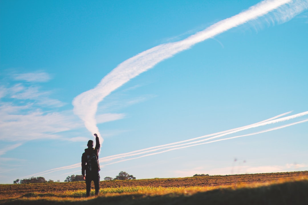 man in black jacket standing on green grass field under blue sky during daytime