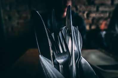 focus photography of silver utensils on container