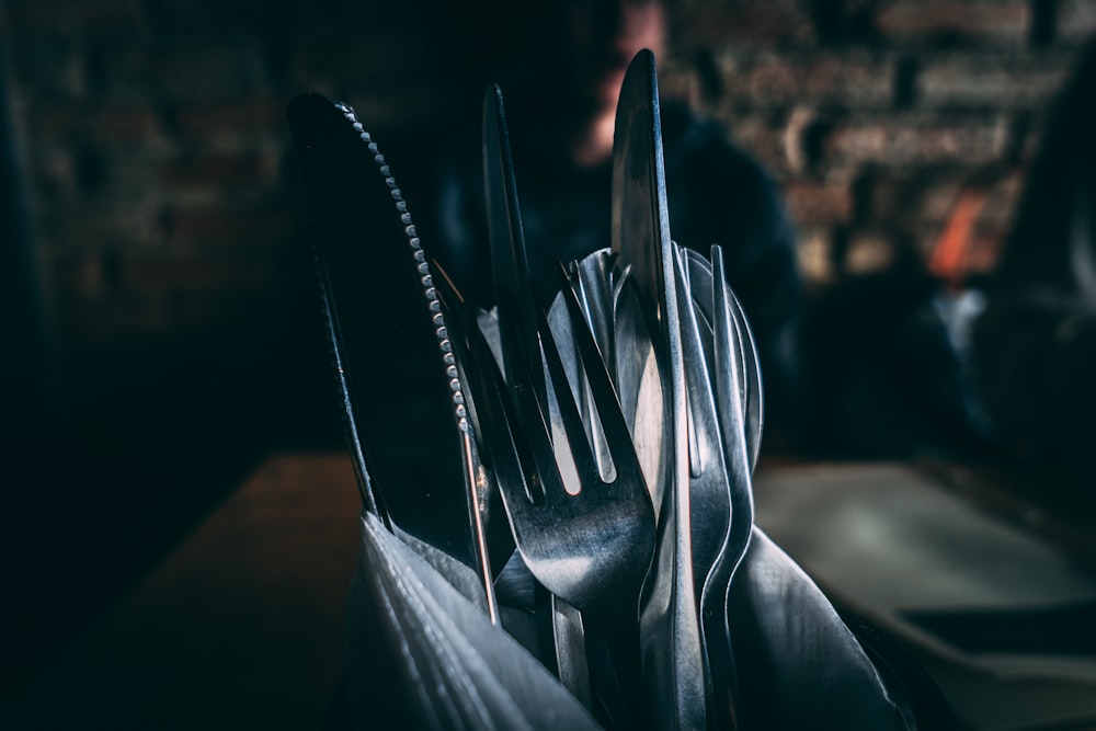 focus photography of silver utensils on container