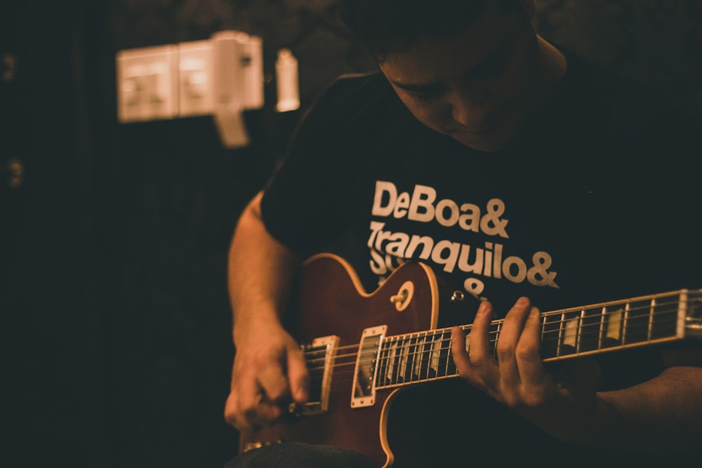 man playing brown guitar