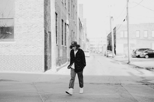 Black and white street scene captured with Ricoh GR, showing a lone figure walking past old brick buildings.