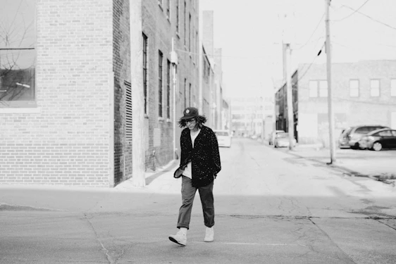 Minimalist black and white photo of a person wearing a simple oversized hoodie walking through an urban street.
