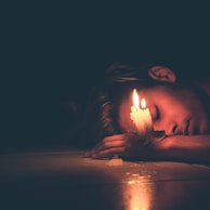 lighted candles on man's hand lying on the floor