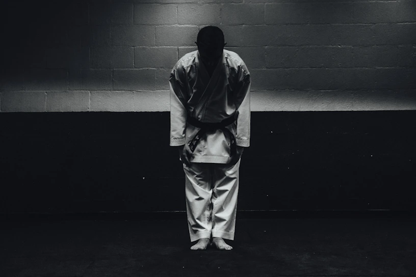 A group of aikido practitioners bowing together in a dojo filled with natural light.