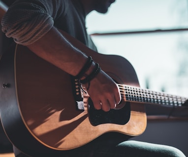 man playing acoustic guitar selective focus photography