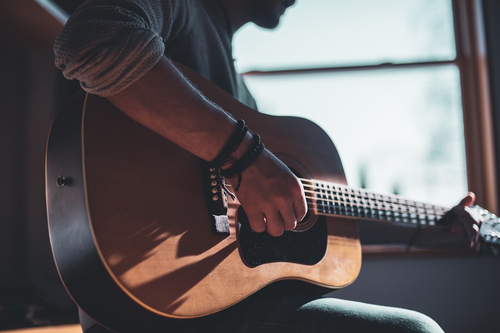 man playing acoustic guitar selective focus photography