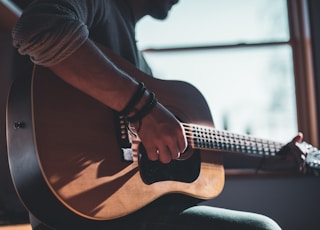 man playing acoustic guitar selective focus photography