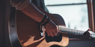 man playing acoustic guitar selective focus photography