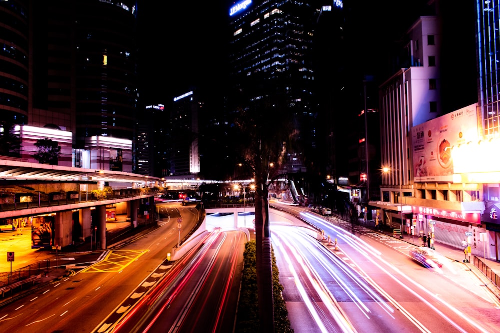 time lapse photography of passing vehicles between high-rise buildings