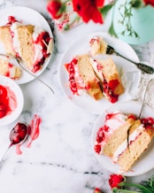 sliced cakes beside stainless steel forks on round white ceramic plates