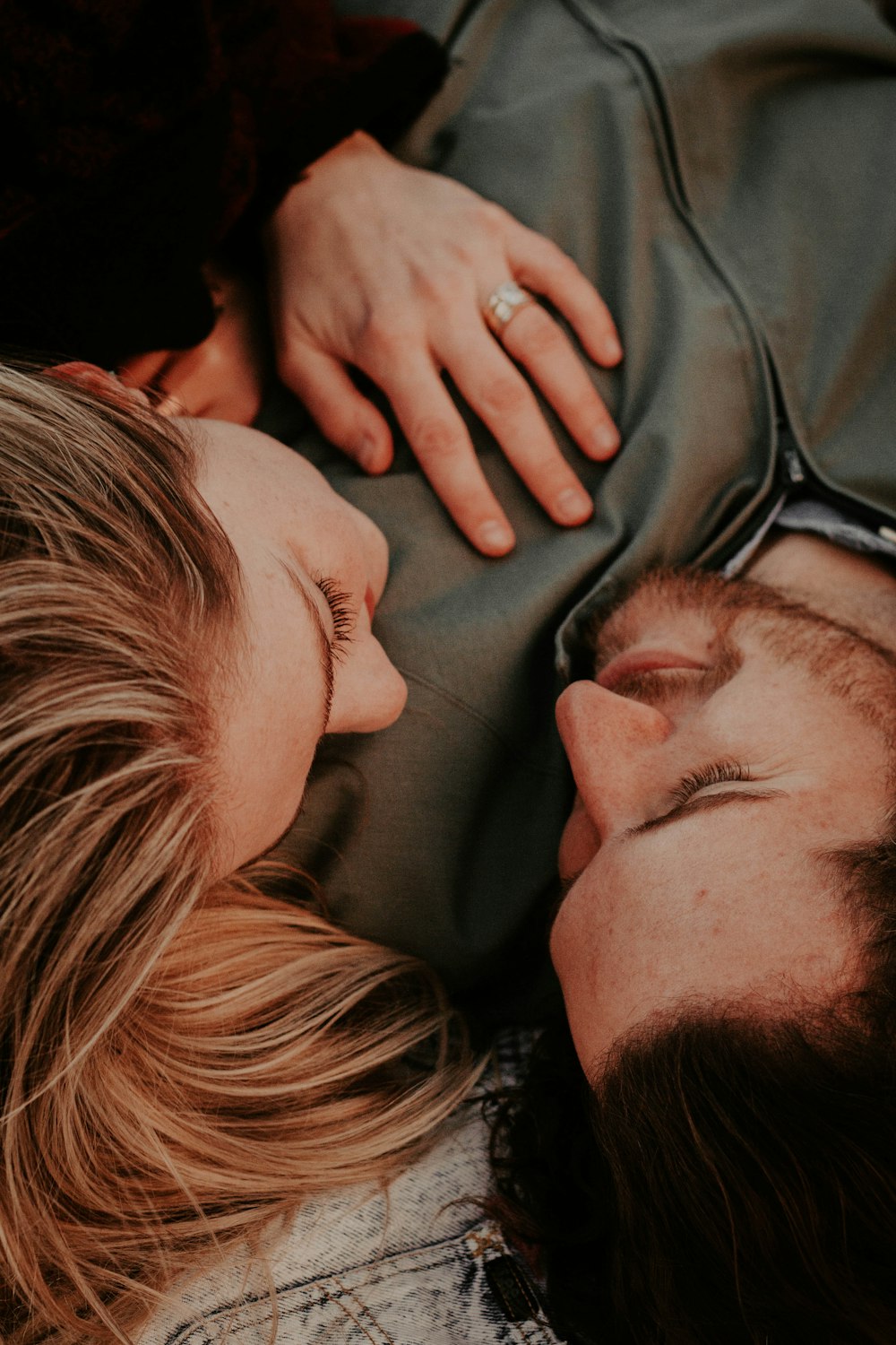 woman beside man lying on gray textile