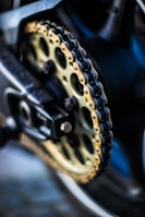 Detailed shot of a motorcycle chain and sprocket glistening under natural light