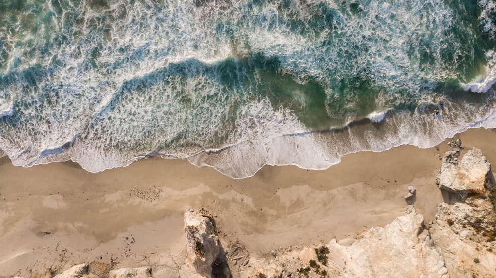 aerial photography body of water splashing on seashore